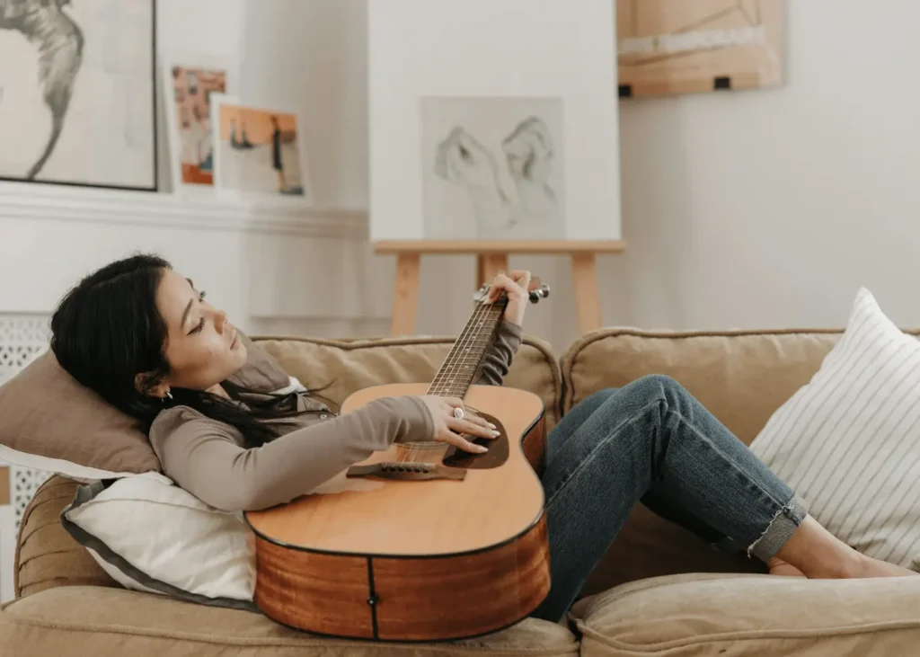 A Woman Lying on the Sofa while Playing Guitar. guitar captions for Instagram